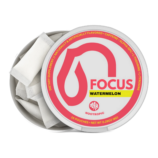 An open round metal tin of Nootropics Focus Watermelon dietary supplement, showing white single-serve pouches inside. The lid features a white label with a prominent pink droplet logo, the word 'FOCUS' in pink, a yellow 'WATERMELON' banner, and the Nootropics logo at the bottom.